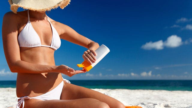Woman taking out sunscreen at the beach