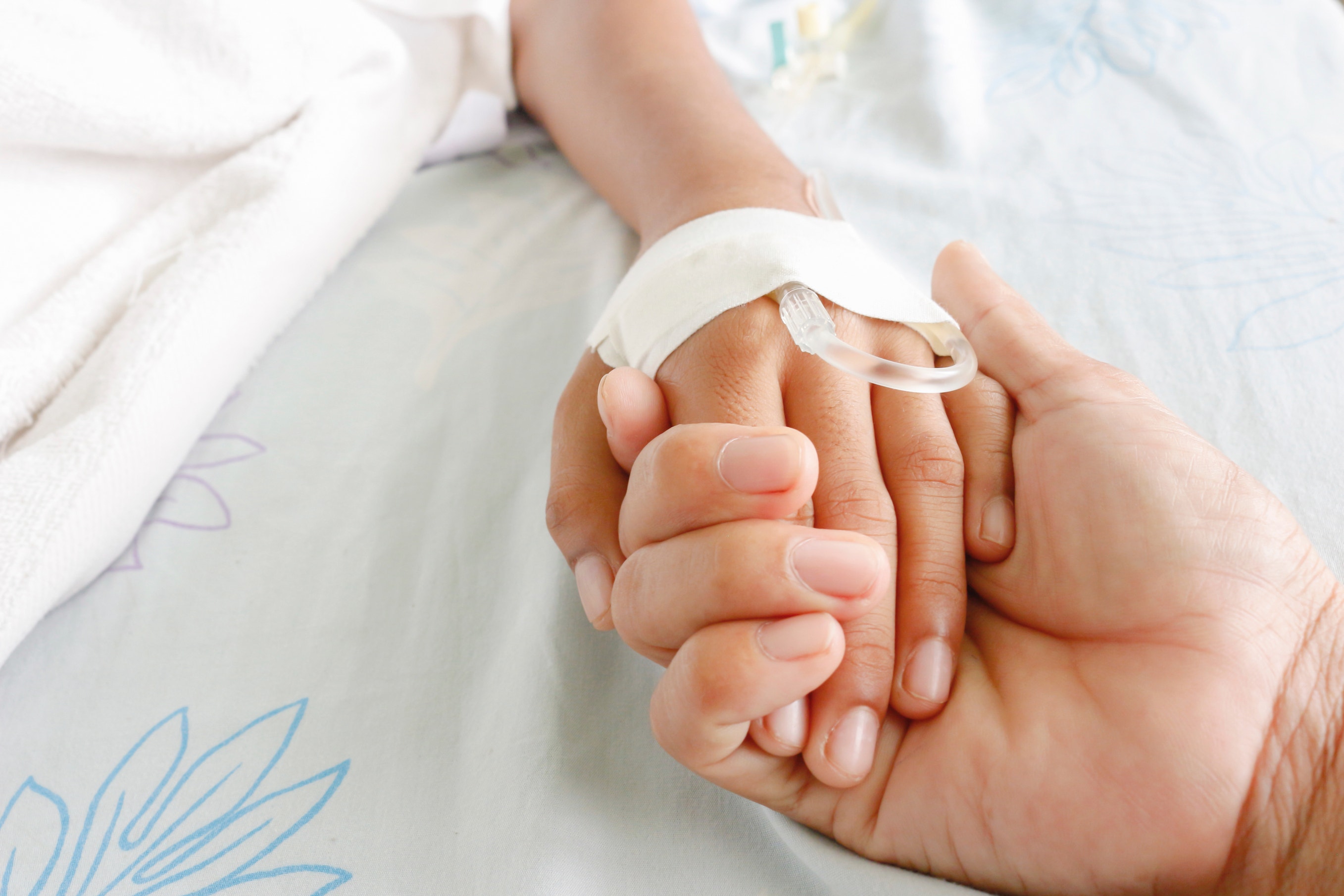 mother holding child's hand who fever patients have IV tube. (iStock)