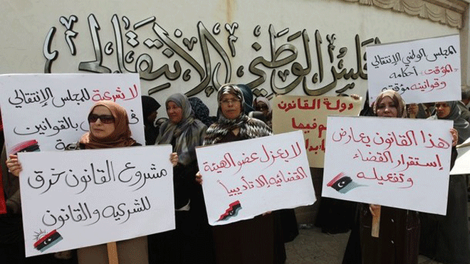 April 26, 2012: Libyan lawyers hold placards during a protest in front of the Transitional Naional Assembly in Tripoli. The placards read: "No legitimacy for the NTC to pass laws" (L) and "this law goes against judicial stability" (2nd R).