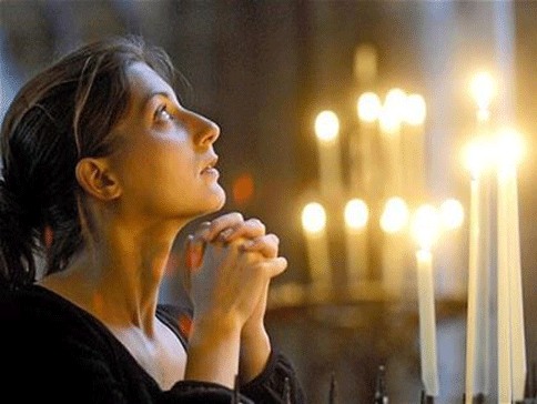 A woman is shown deep in prayer in this image. 