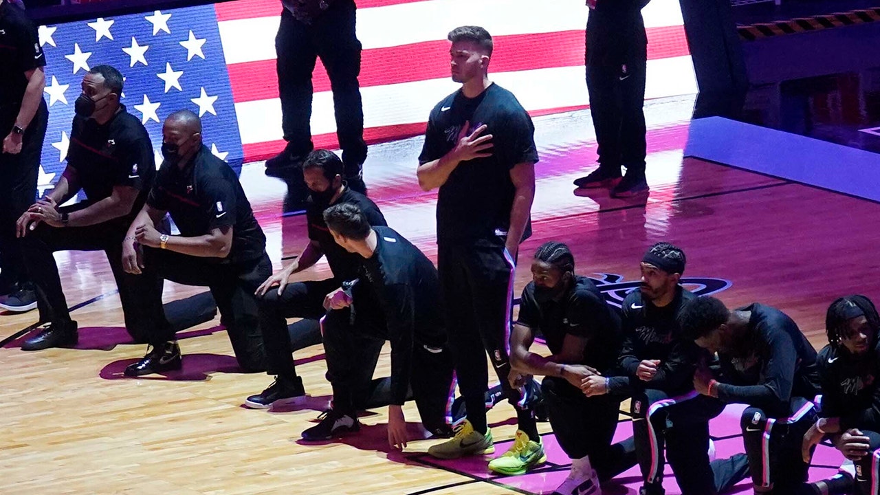 Heat’s Meyers Leonard represents the national anthem, while teammates, Celtics players kneel