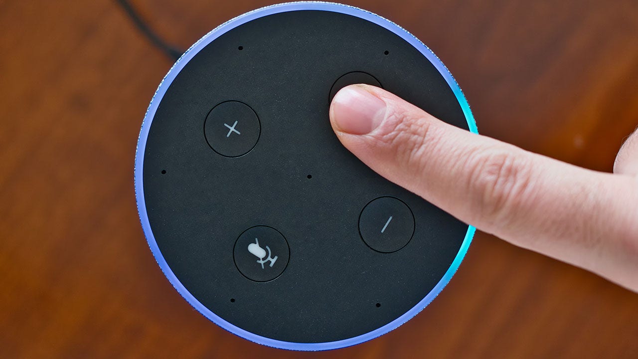 A finger pressing a button on an Amazon Echo device