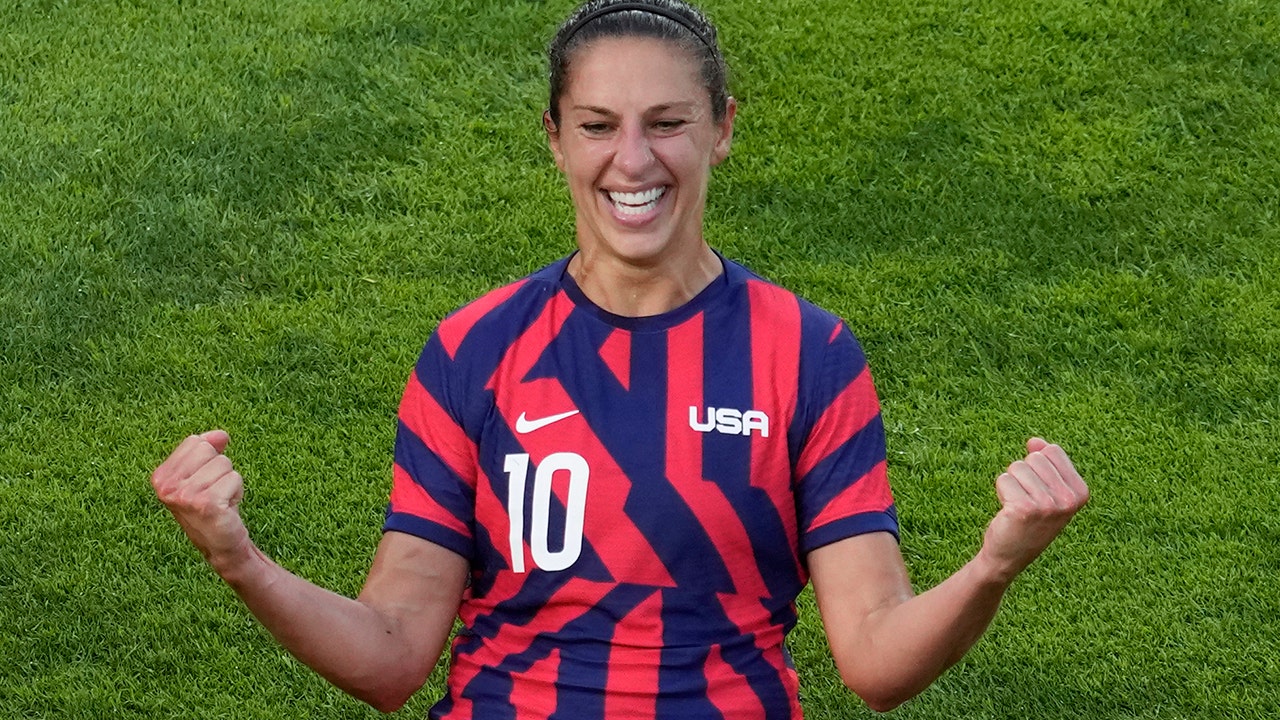 Carli Lloyd in piedi e le sue compagne di calcio in ginocchio prima della partita per la medaglia di bronzo