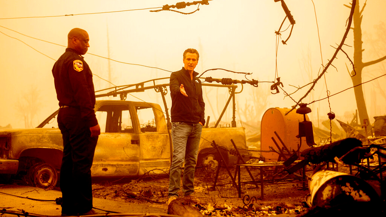 California Gov. Gavin Newsom examines a scorched utility pole while surveying Dixie Fire damage in Greenville on Saturday, Aug. 7, 2021, in Plumas County, Calif. Accompanying him is Cal Fire Assistant Region Chief Curtis Brown. 