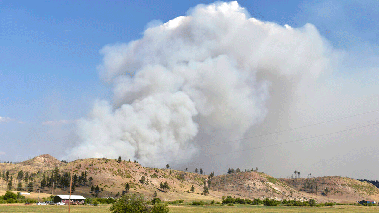 A plume of smoke rises from the Richard Spring wildfire on Wednesday, Aug. 11, 2021, north of Lame Deer, Mont. The fire spread quickly Wednesday as strong winds pushed the flames across rough, forested terrain. 