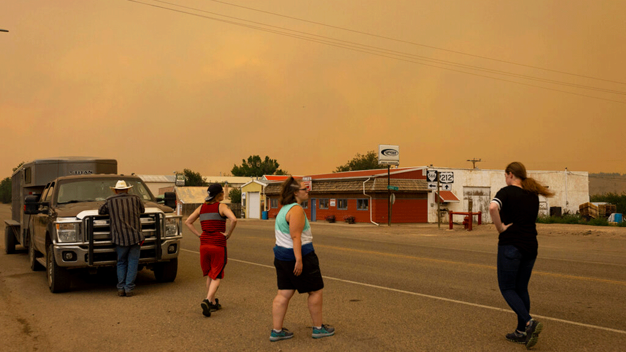 People are seen on the street as a wildfire approaches the town, Tuesday, Aug. 10, 2021, in Ashland, Mont. The Richard Spring Fire was threatening hundreds of homes in Ashland and on the nearby Northern Cheyenne Indian Reservation. 