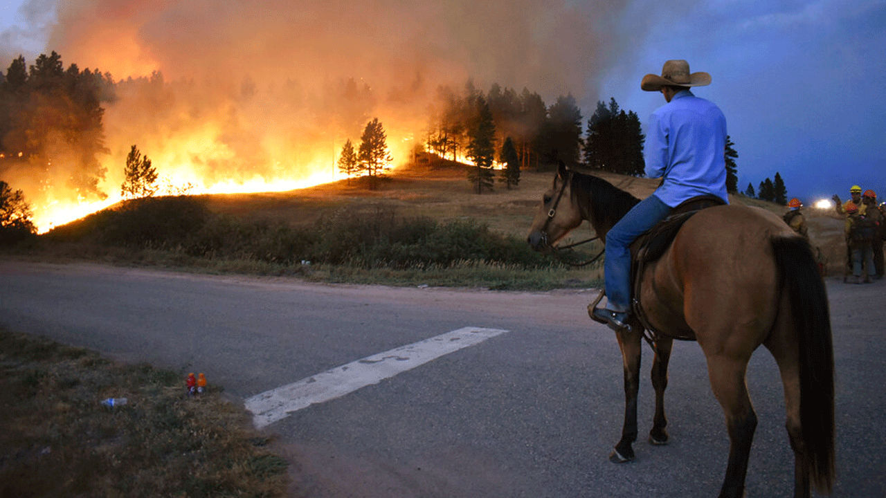 Rowdy Alexander watches from atop his horse as a hillside burns on the Northern Cheyenne Indian Reservation, Wednesday, Aug 11, 2021, near Lame Deer, Mont. The Richard Spring fire was threatening hundreds of homes as it burned across the reservation. 