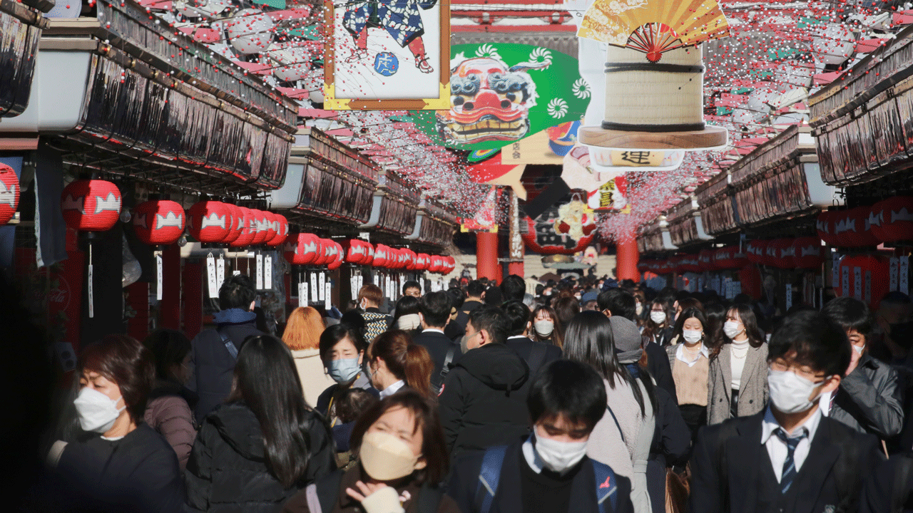 People wearing face masks to protect against the spread of the coronavirus walk under decorations for new year through the alley leading to Asakusa Sensoji Buddhist temple in Tokyo on Dec. 21, 2021. 