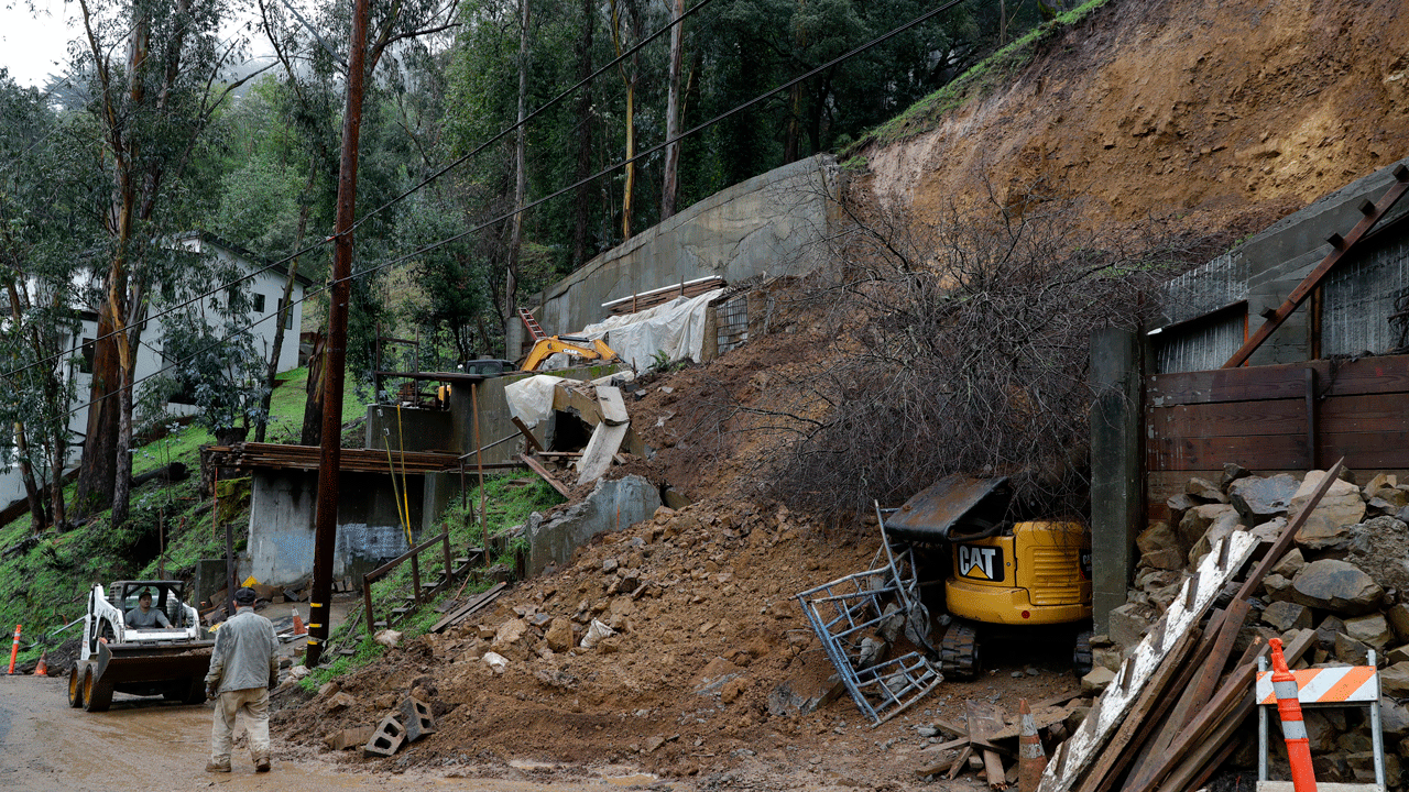 Workers clear a mudslide from a double lot on Westover Drive in Oakland, California, on Thursday, Dec. 23, 2021. (Associated Press)