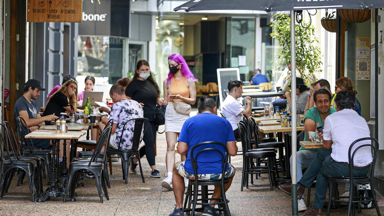 Customers eat outside at cafes in central Auckland, New Zealand, on Friday, December 3, 2021. Bars, restaurants and gyms reopened in Auckland on Friday as the last major parts of the more than 100-day lockdown ended.  New Zealand has begun a new phase in its virus response in which there will be no lockdown but people will be required to show permits for vaccinations for many services.  (Alex Burton/NZ Herald via AP)