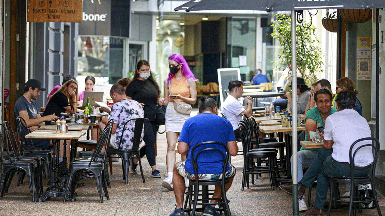 Patronii iau masa la cafenelele din centrul Auckland, Noua Zeelandă, vineri, 3 decembrie 2021. Barurile, restaurantele și sălile de sport s-au redeschis vineri în Auckland, după ce ultimele părți majore ale unui blocaj care a durat mai mult de 100 de zile s-au încheiat.  Noua Zeelandă a intrat într-o nouă fază în răspunsul său la virus în care nu va exista blocare, dar oamenii vor trebui să prezinte permise de vaccin pentru multe servicii.  (Alex Burton / NZ Herald prin AP)