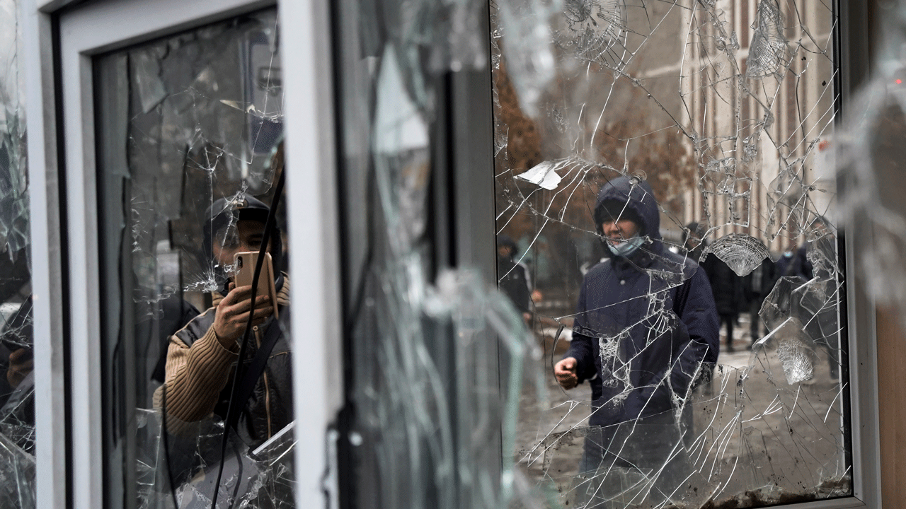 A man takes a photo of windows of a police kiosk damaged by demonstrators during a protest in Almaty, Kazakhstan, Wednesday, Jan. 5, 2022. (AP Photo/Vladimir Tretyakov)