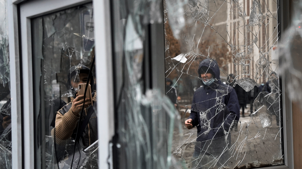 A man takes a photo of windows of a police kiosk damaged by demonstrators during a protest in Almaty, Kazakhstan, Wednesday, Jan. 5, 2022.