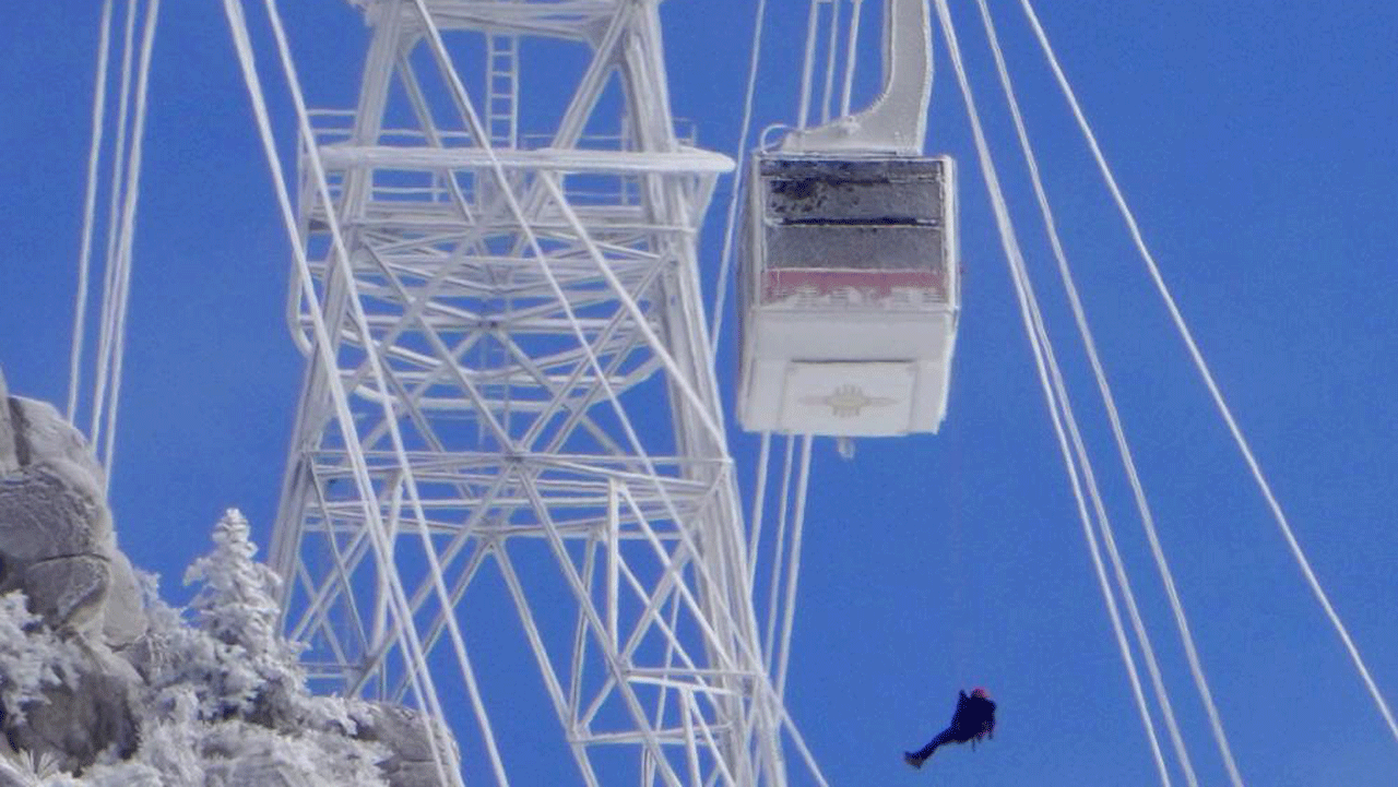 A passenger is lowered from a Sandia Peak Tramway car that was stranded overnight on New Year's Eve on Saturday, Jan. 1, 2022, in Albuquerque, N.M. A Bernalillo County Fire Department spokesman said 16 of the stranded people were rescued as of Saturday afternoon as rescue operations continued. The spokesman said those aboard the car when it got stuck at 10 p.m. Friday were all employees of the Sandia Peak Aerial Tramway or a mountaintop restaurant. (Roberto E. Rosales /The Albuquerque Journal via AP)