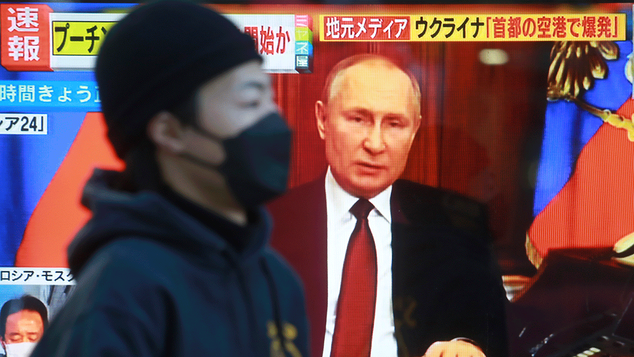 A man walks past a TV screen with an image of Russia's President Vladimir Putin in Tokyo, Thursday, Feb. 24, 2022. 