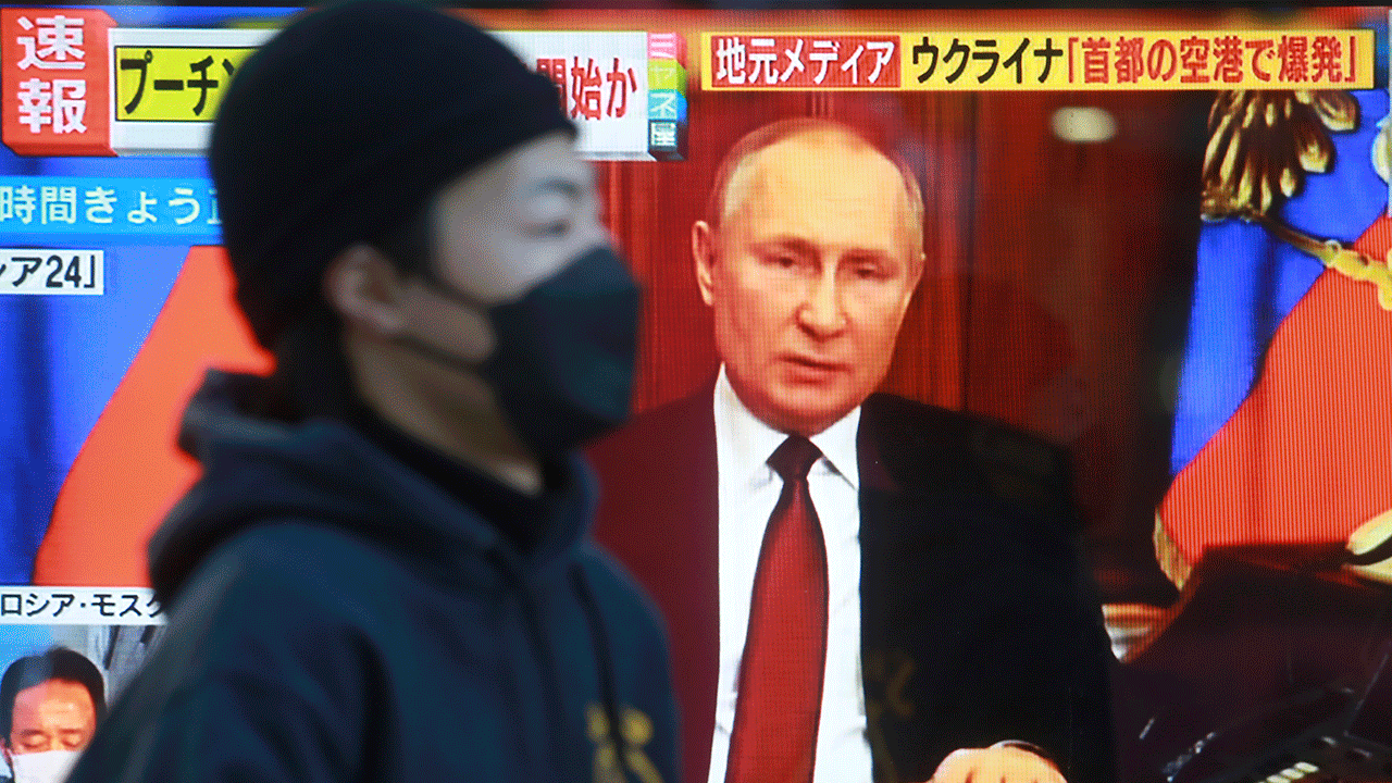 A man walks past a TV screen with an image of Russia's President Vladimir Putin in Tokyo, Thursday, Feb. 24, 2022. 