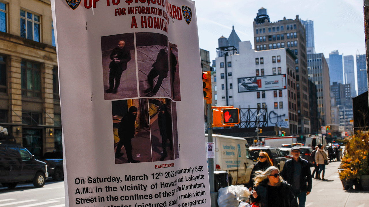 People walk by a bulletin posted by NYPD near the place where a homeless person was killed days earlier in lower Manhattan, Monday, March 14, 2022, in New York. 