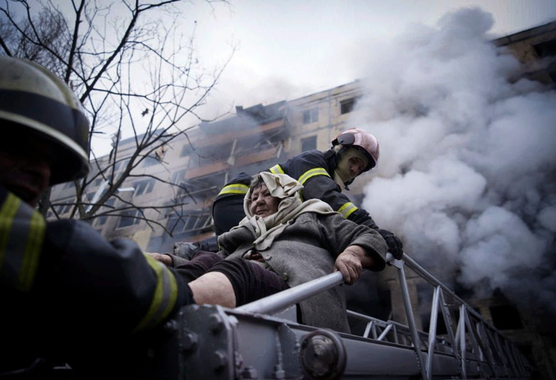 In this photo released by Ukrainian State Emergency Service press service, firefighters evacuate an elderly woman from an apartment building hit by shelling in Kyiv, Ukraine, Monday, March 14, 2022. (Ukrainian State Emergency Service via AP)