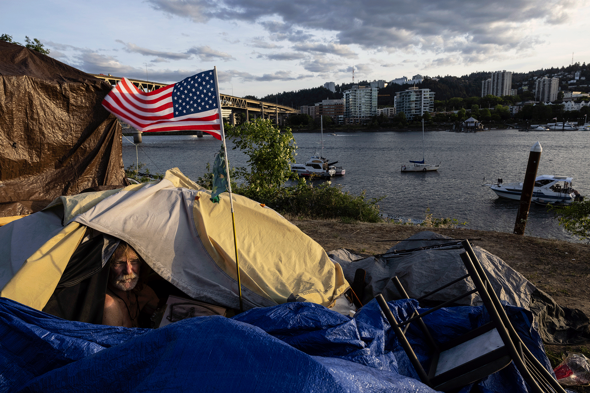 Frank, que se encuentra sin hogar, se sienta en su tienda de campaña en Portland, Oregón, junto al río Willamette, el 5 de junio de 2021. 