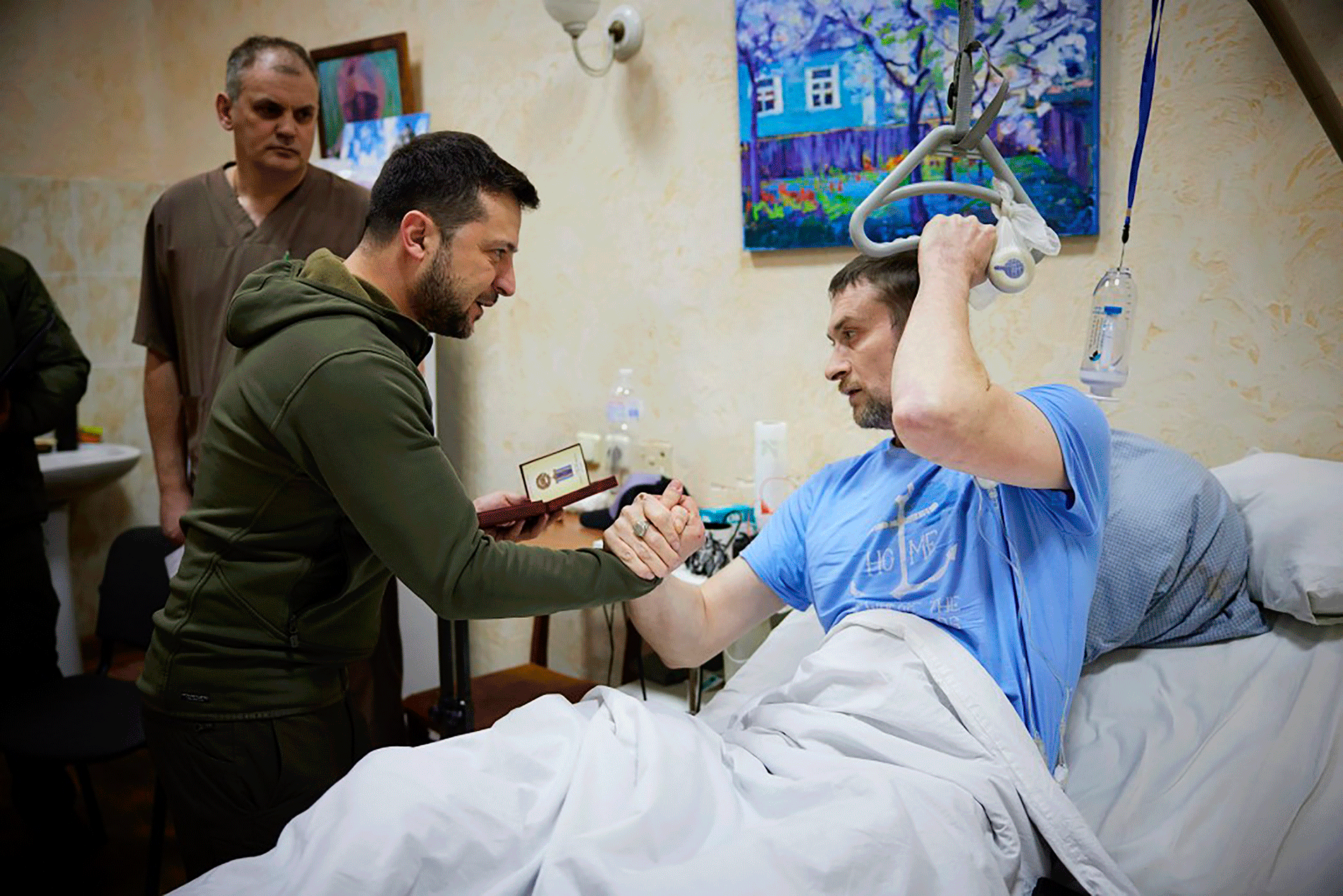 In this photo provided by the press service of the President of Ukraine on Sunday, March 13, 2022, President Volodymyr Zelensky (center) shakes the hand of a wounded soldier during his visit to a hospital in Kyiv, Ukraine.