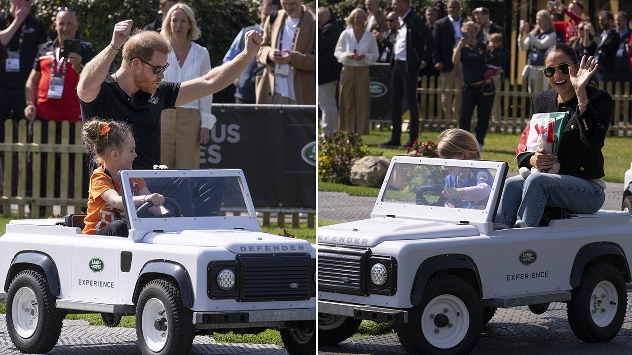 Prințul Harry și Meghan Markle zâmbesc în timp ce merg cu un mini Land Rover la evenimentul Invictus Games