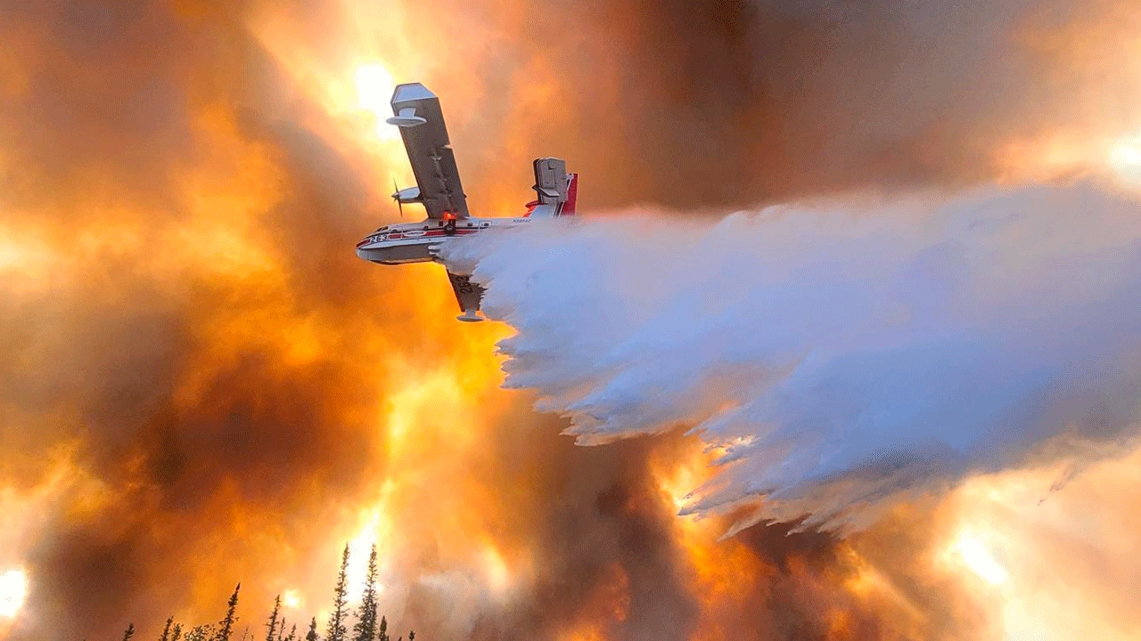 FILE - In this photo provided by Eric Kiehn, Northwest Incident Management Team 10, Alaska Division of Forestry, a fixed-wing aircraft drops water on the Clear Fire near Anderson, Alaska, on July 6, 2022. Alaska's remarkable wildfire season includes over 530 blazes that have burned an area more than three times the size of Rhode Island, with nearly all the impacts, including dangerous breathing conditions from smoke, attributed to fires started by lightning. 
