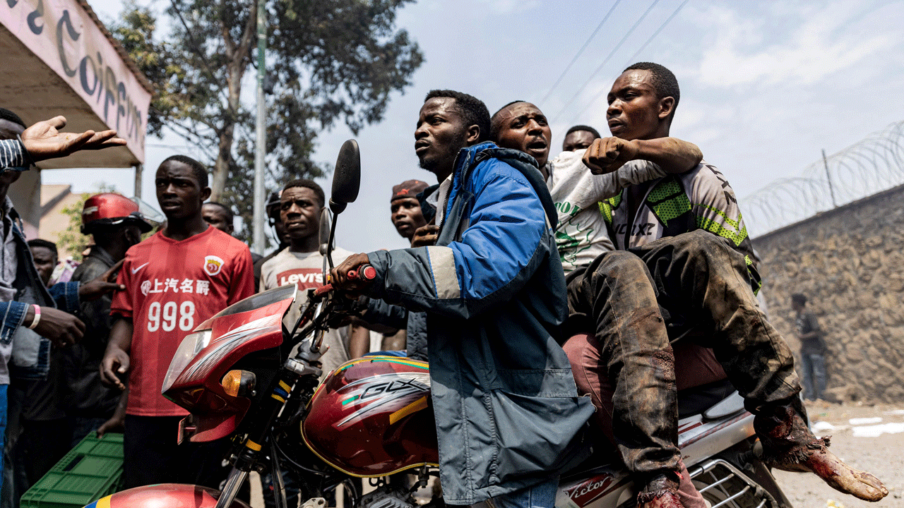 A wounded man is rushed away on a motorcycle after protesters stormed and looted a warehouse belonging to the peacekeeping mission in the Democratic Republic of Congo (MONUSCO) at the UN facilities in Goma on July 25, 2022. - Protesters stormed a United Nations base in the eastern Congolese city of Goma today, an AFP journalist said, demanding the departure of peacekeepers from the region. 