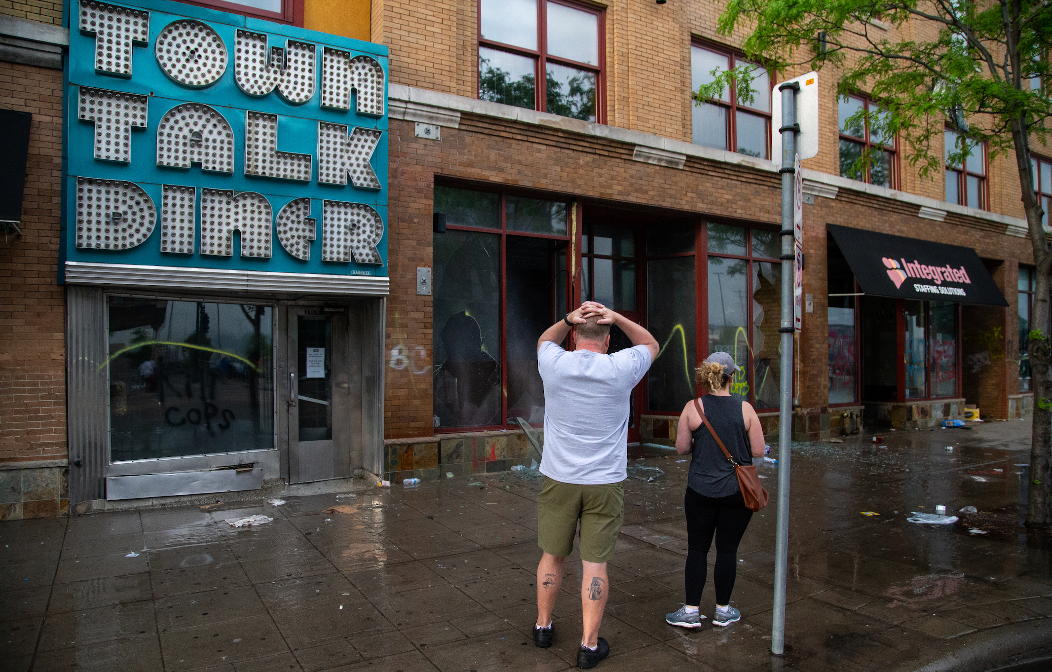 Charles Stotts and wife Kacey White, owners of Town Talk Diner on Lake Street in Minneapolis, watch as water pours out of the restaurant on Thursday, May 28, 2020. The building had been looted the night before. 