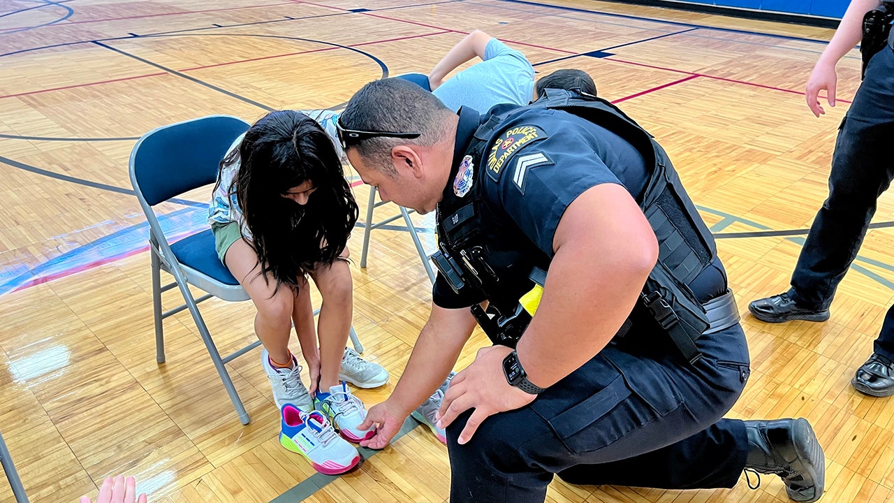A police officer in Dallas, Texas, helps students try on new sneakers ahead of back-to-school time this year. (Lisa C. Coleman, Energy Transfer)
