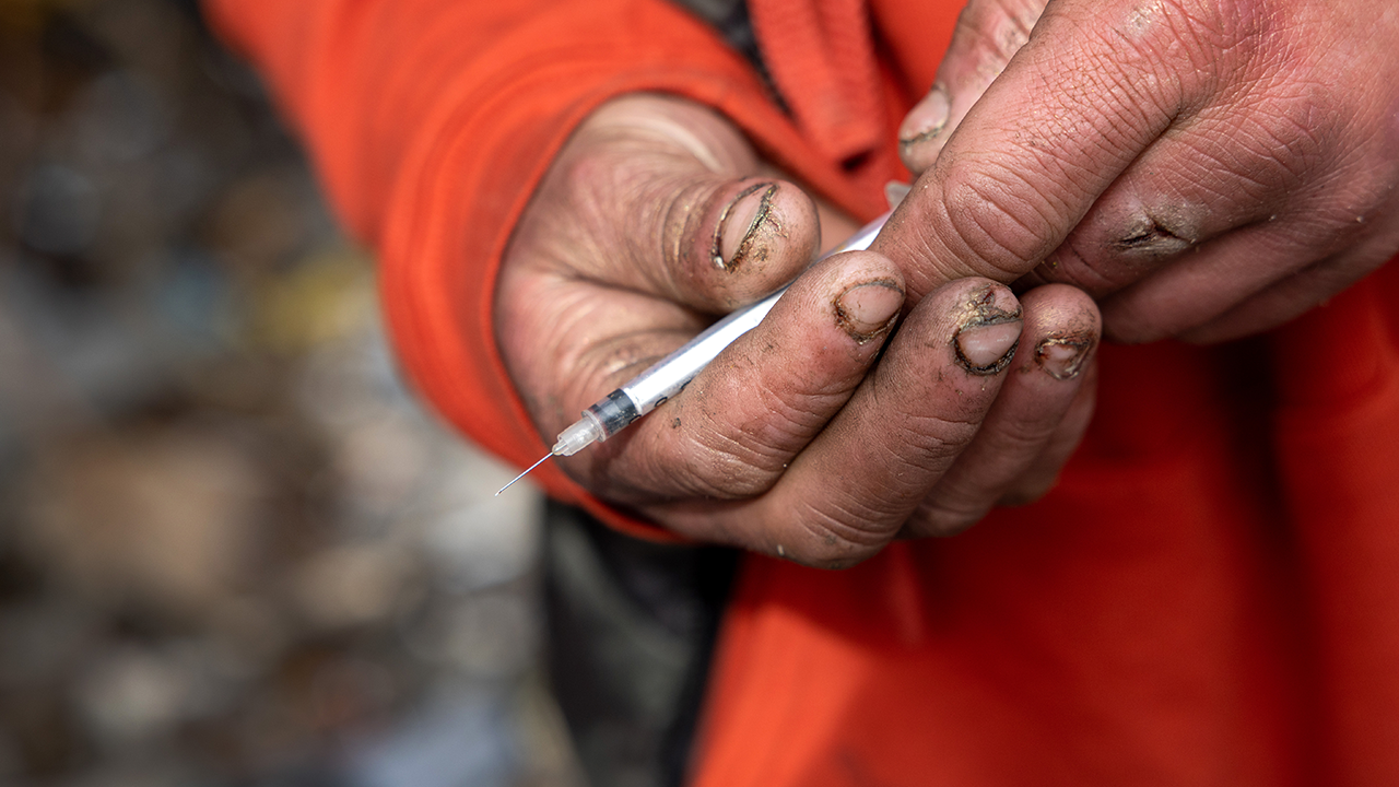 Man in Seattle holding a needle for meth use