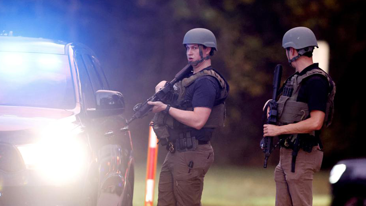 Law enforcement stand at the entrance to Neuse River Greenway Trail parking at Abington Lane following a shooting in Raleigh, N.C., Thursday, Oct. 13, 2022. (Ethan Hyman/The News & Observer via AP)