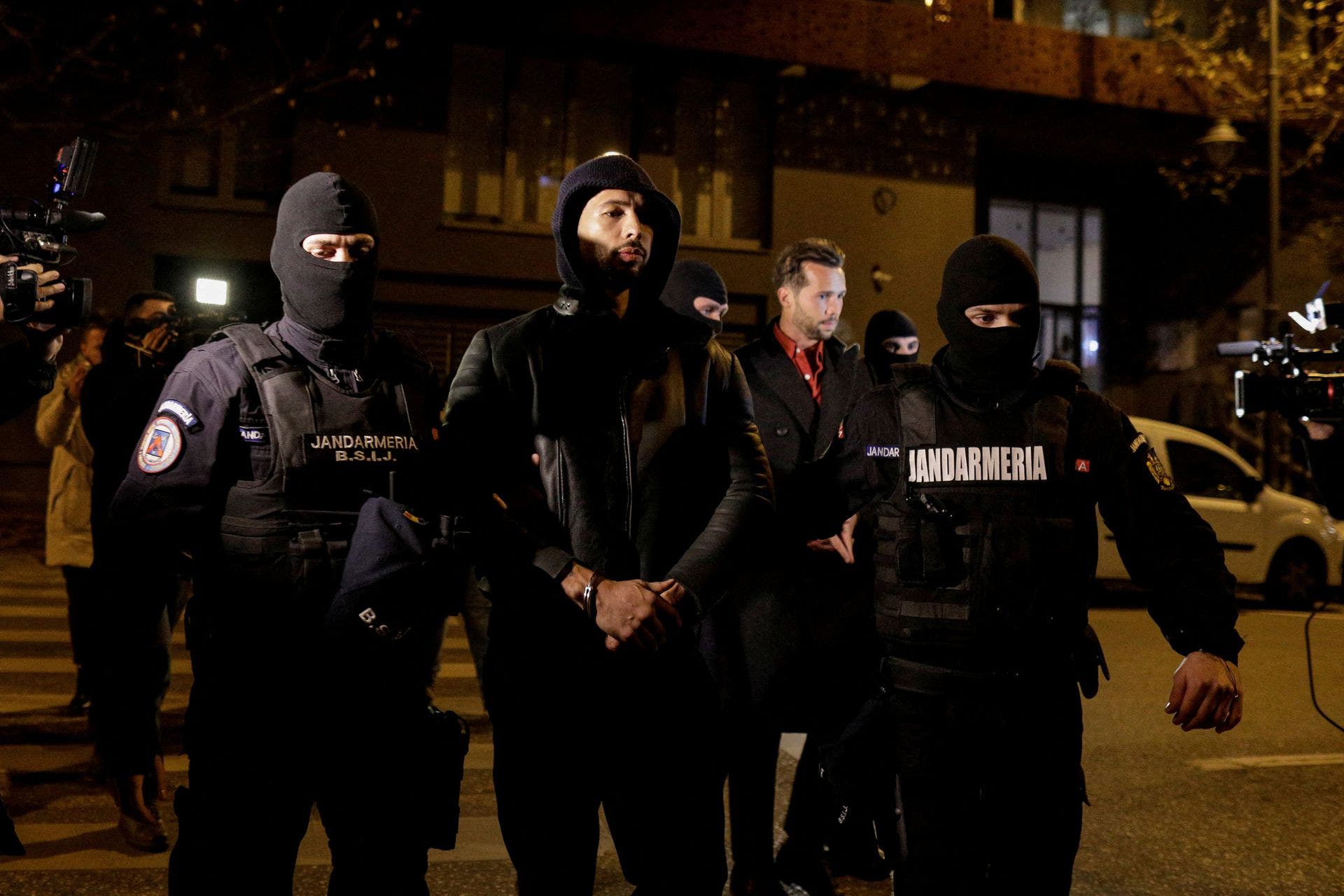 Andrew Tate and Tristan Tate are escorted by police officers outside the headquarters of the Directorate for Investigating Organized Crime and Terrorism in Bucharest (DIICOT) after being detained for 24 hours, in Bucharest, Romania, December 29, 2022. Inquam Photos/Octav Ganea via REUTERS (Reuters)