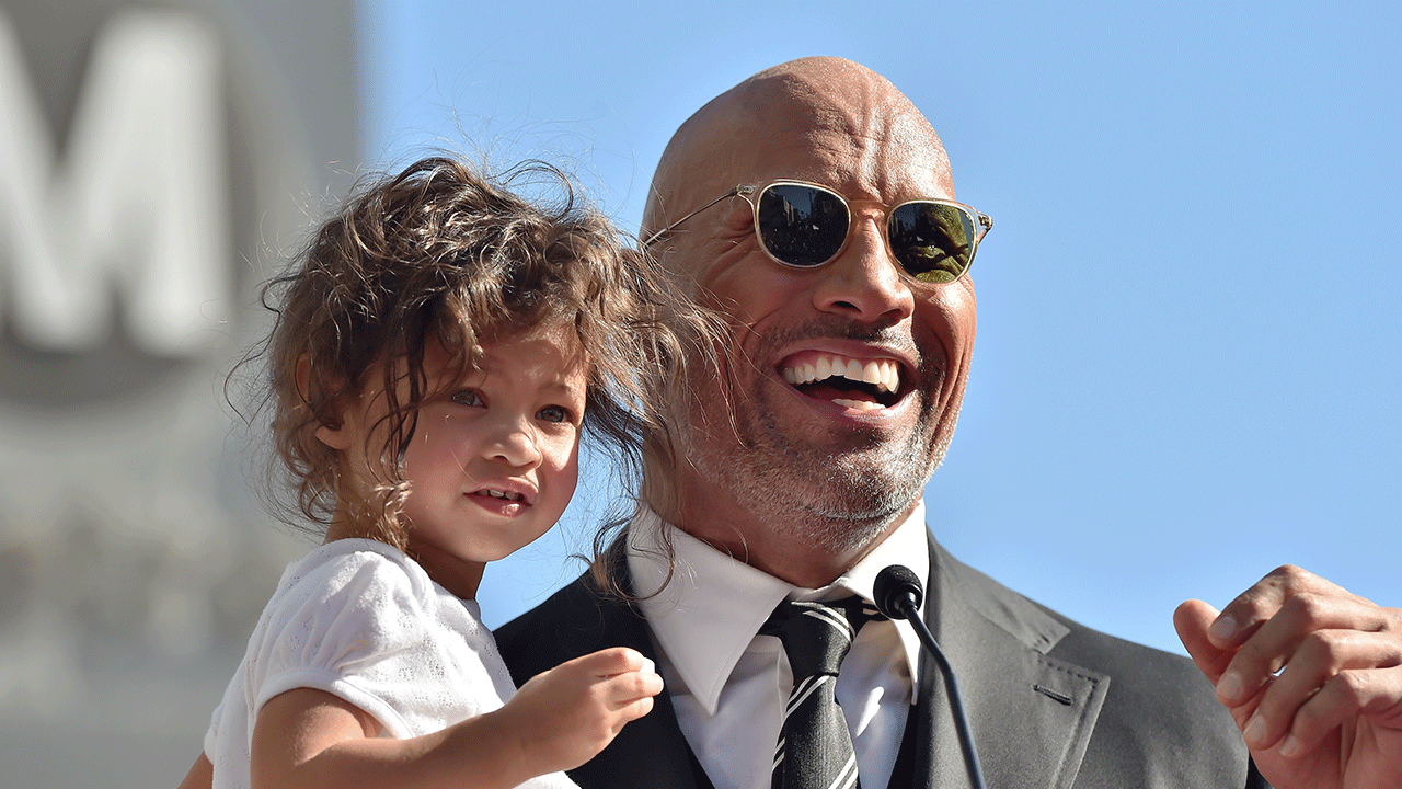 Dwayne Johnson held daughters Jasmine and Tiana on the sidelines of an NFL game on Sunday as they watched Lauren Hashian sing the National Anthem. 