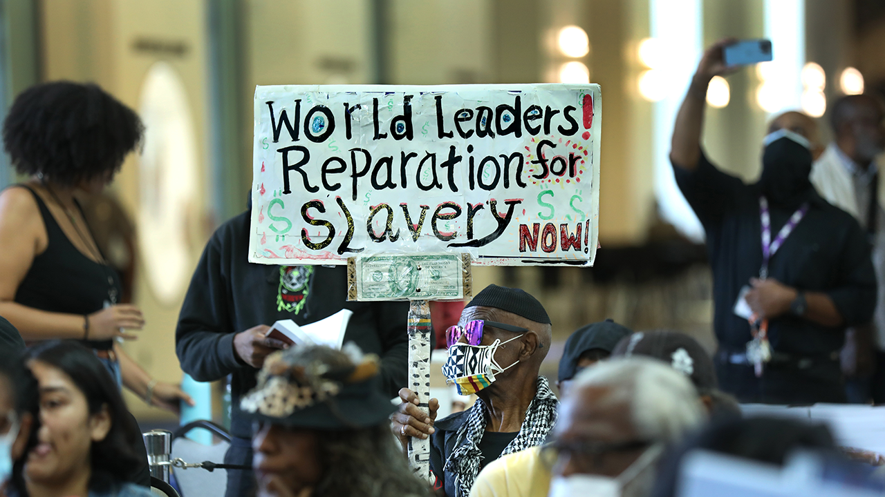 Der langjährige Einwohner von Los Angeles, Walter Foster, 80, hält ein Schild hoch, während sich die Reparations Task Force am 22. September 2022 im California Science Center in Los Angeles trifft, um öffentliche Meinungen zu Reparationen anzuhören.