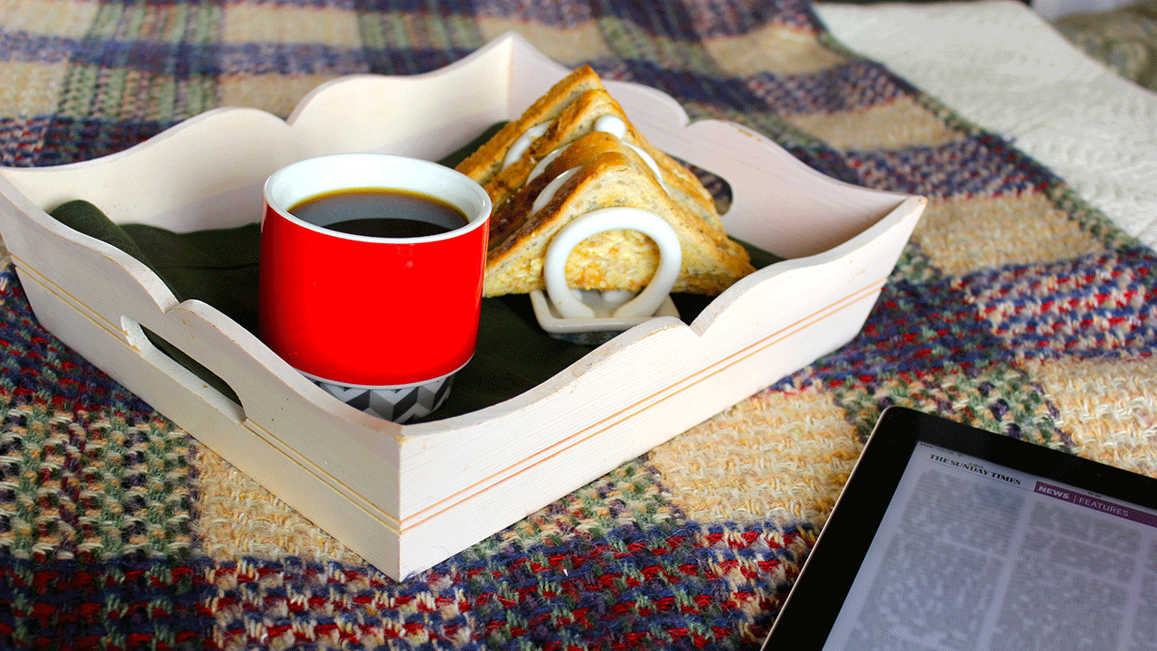 Tray on a bed with a coffee mug and toast