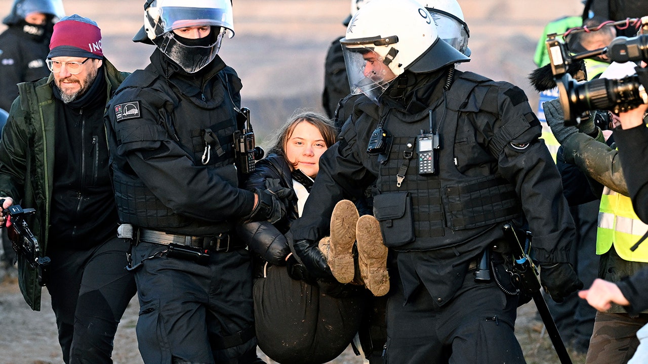 Greta Thunberg smiles as German police carry her away during environmental protest over coal mine expansion