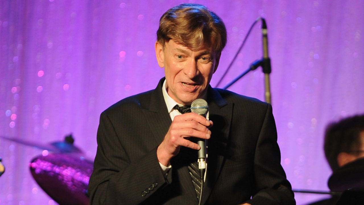 Bobby Caldwell singing into a microphone while on stage