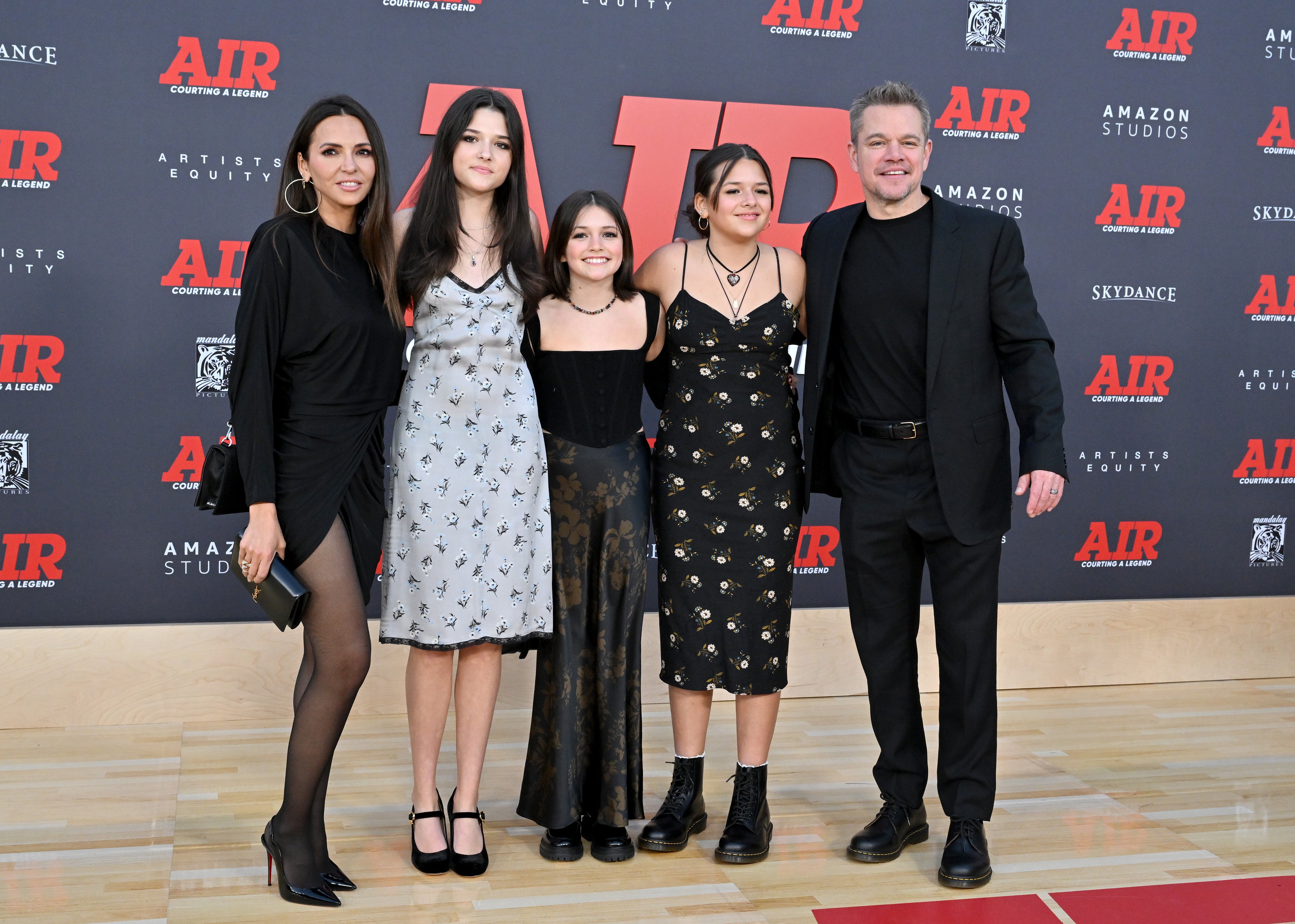 Luciana Barroso, Matt Damon, and three of their daughters pose in coordinating black ensembles on the carpet