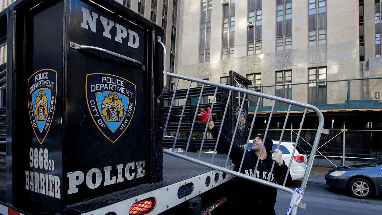 Workers with the New York Police Department set up barricades outside the Manhattan District Attorney's office in New York City on March 20, 2023. Former President Trump said he expects to be "arrested" on Tuesday, March 21, 2023, over an alleged hush-money payment to a porn star in 2016, and he urged his supporters to protest, as prosecutors gave signs of moving closer to an indictment.