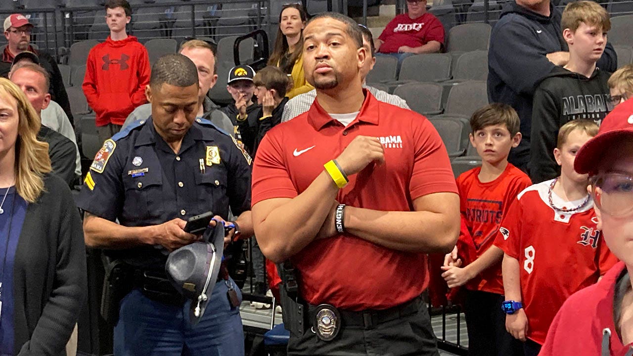 Brandon Miller de Alabama acompañado por un guardia de seguridad armado durante la práctica de March Madness