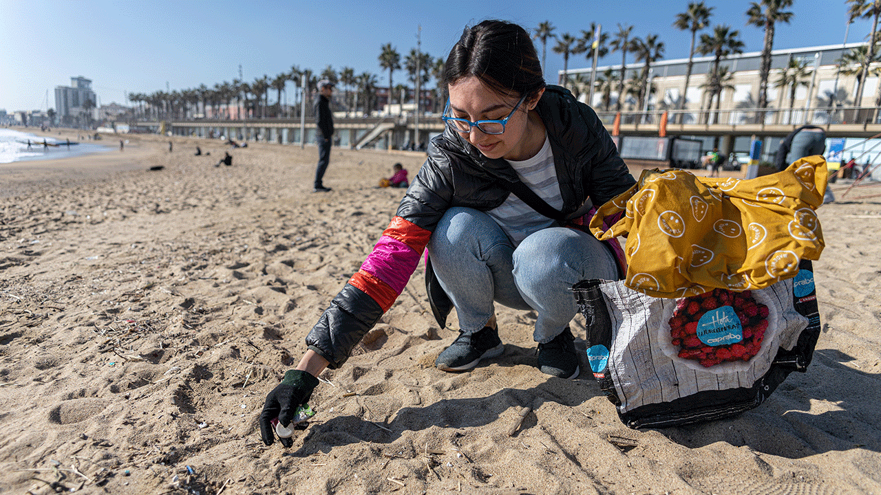 A volunteer picking up trash on a beach