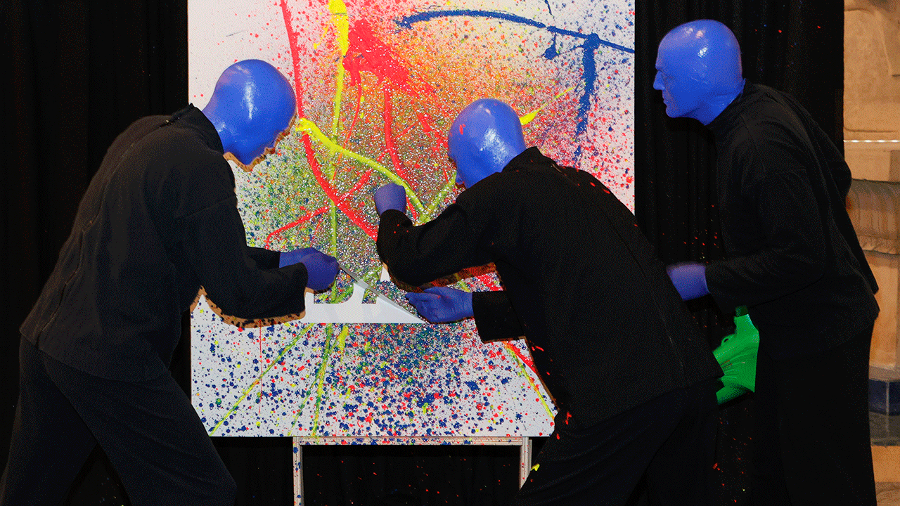 The Blue Man Group painting on canvas during a show