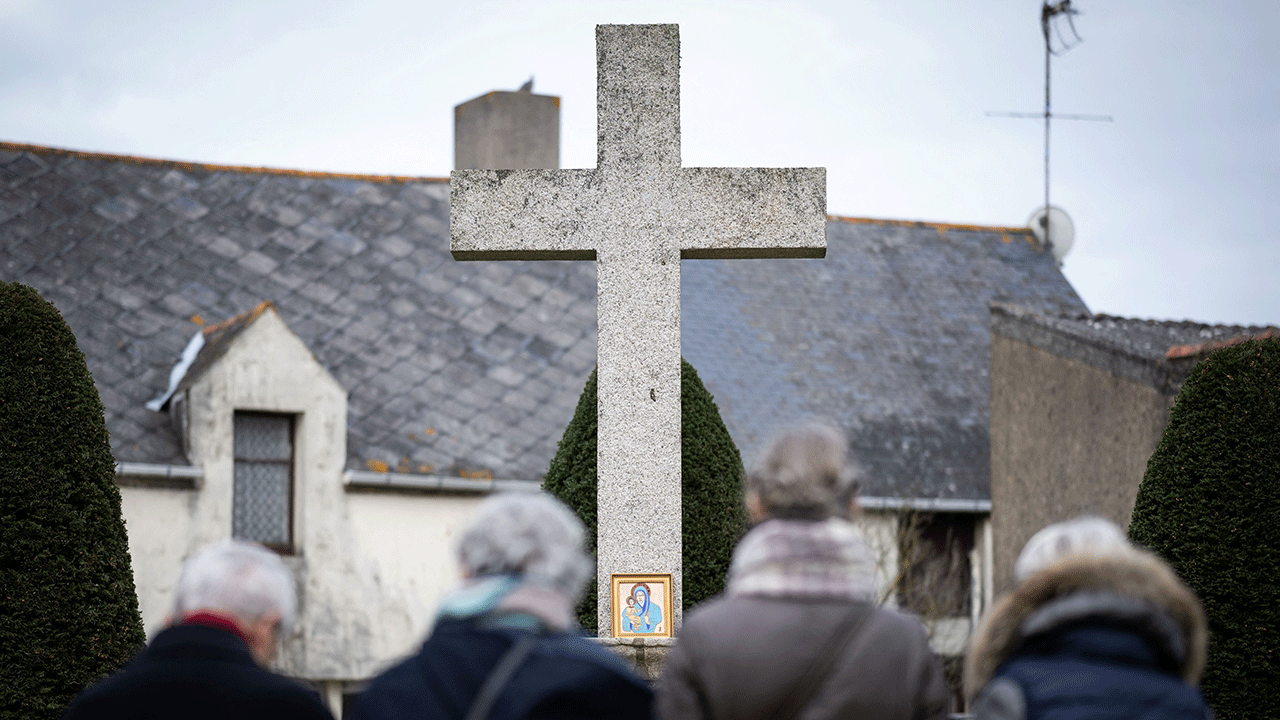 People standing in front of a cross