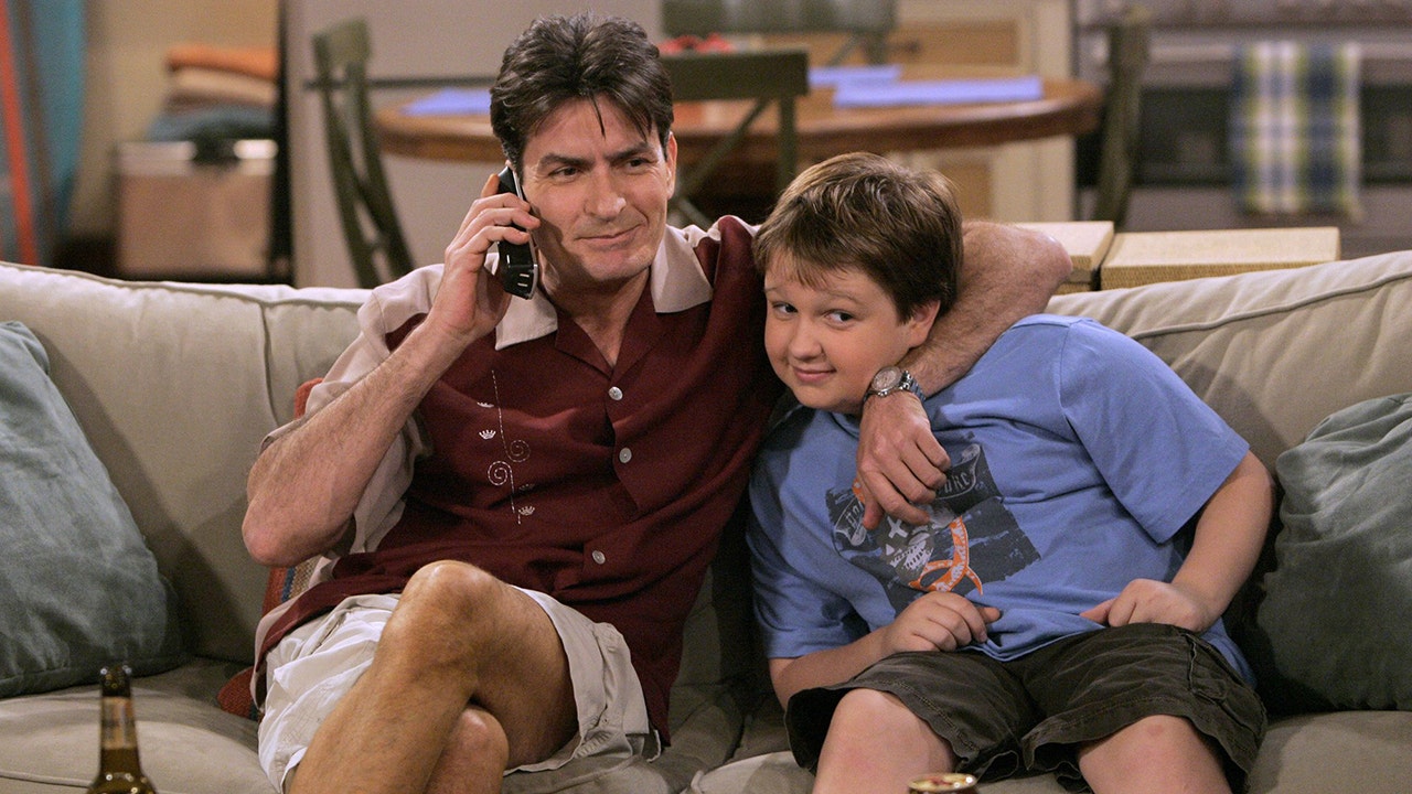 Charlie Sheen raps his arm around a young Angus T. Jones on the set of 