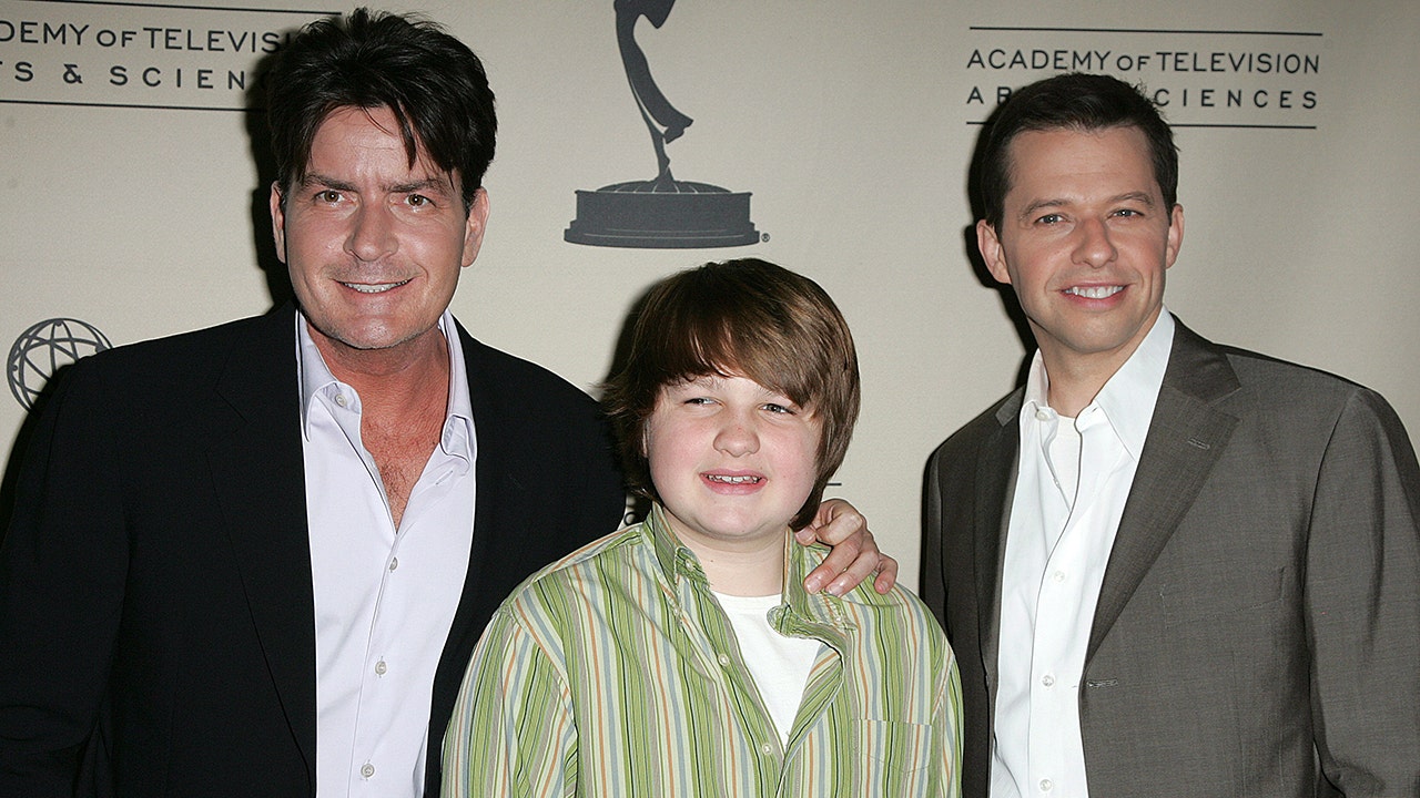 Charlie Sheen holds on to Angus T. Jones next to Jon Cryer at an event for 