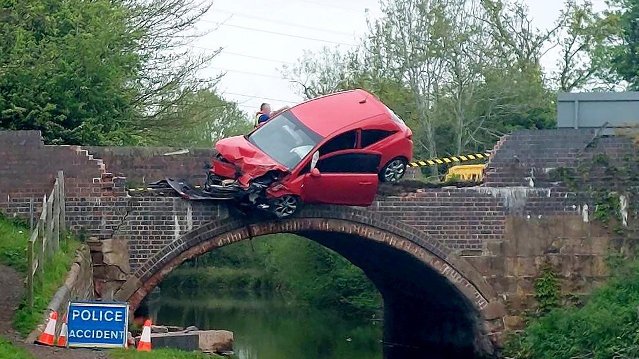 Car crash results in wild dangle over bridge as passenger finds novel way to escape