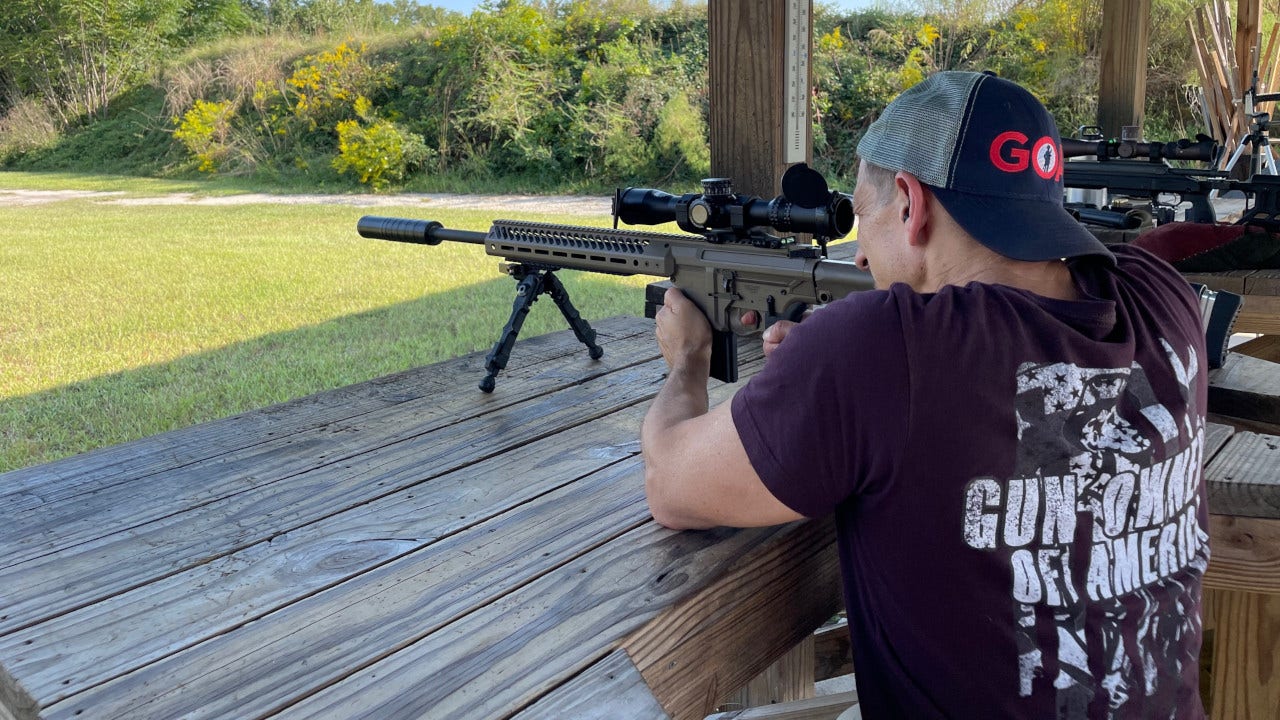 Ein Mann, der Merchandise-Artikel von Gun Owners of America trägt, schießt mit einem Gewehr