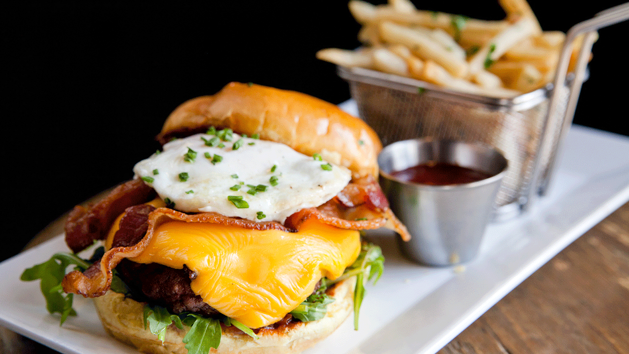 Hamburger topped with and egg and fries on the side