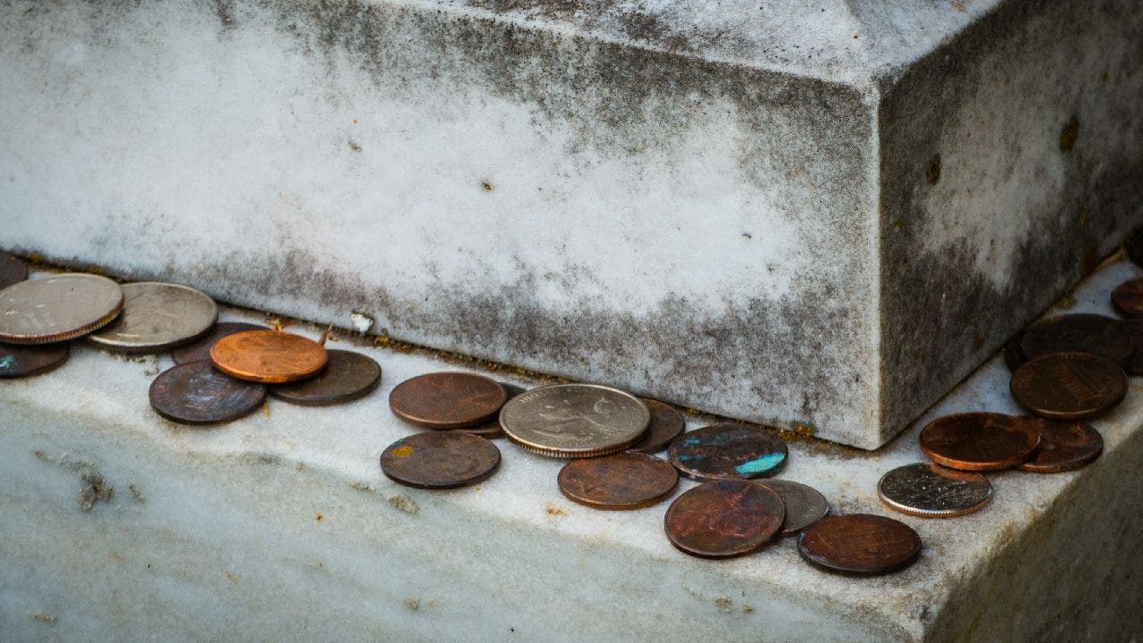 Coins left on the edge of a headstone