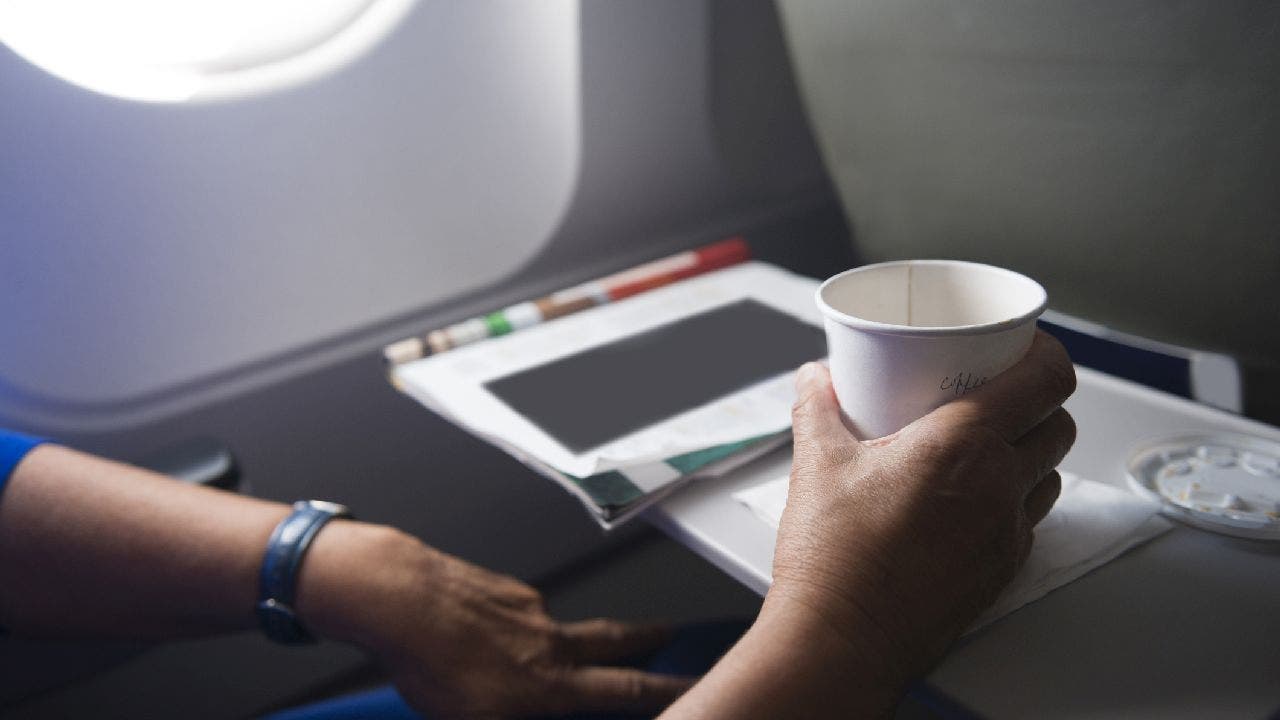 Airplane passenger uses tray hold cup